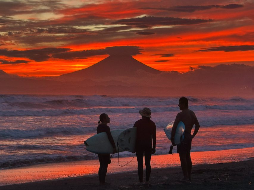 Surfers on the shore with Mount Fuji behind them